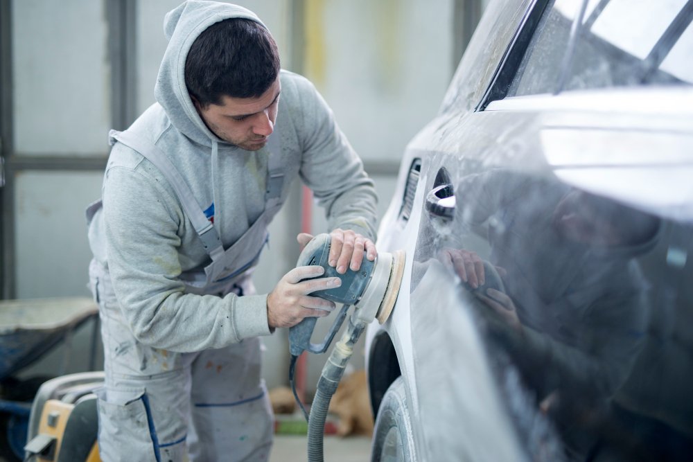 Mechanic inspecting or detailing repaired car surface